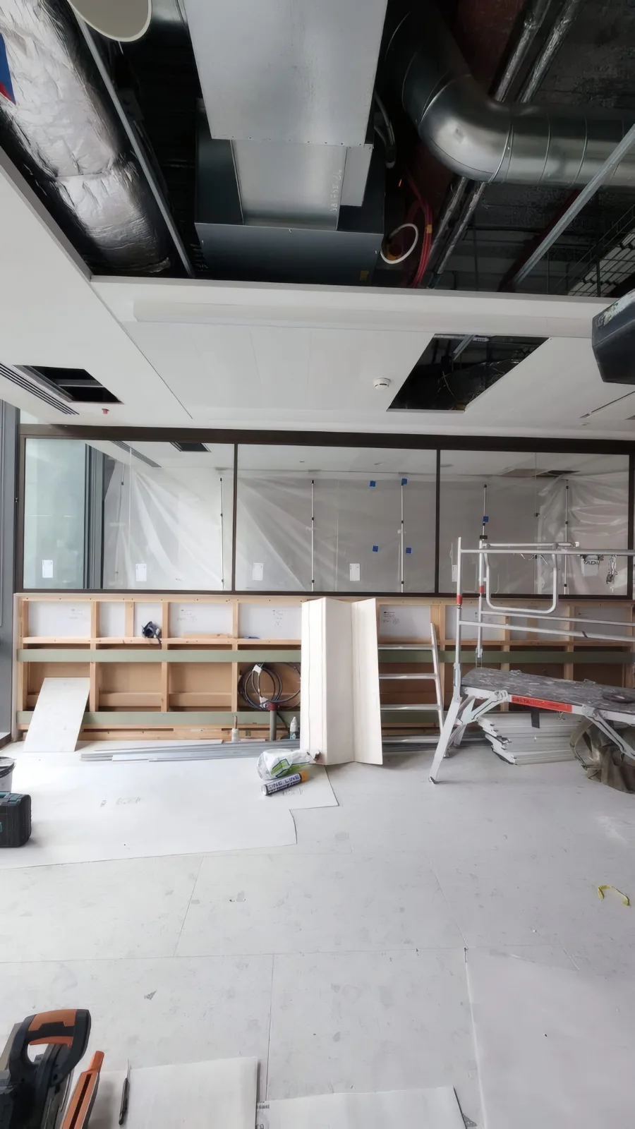Glazed partition installation in progress, with protective tape still in place on the framing during the wider Cat A/Cat B fit-out.