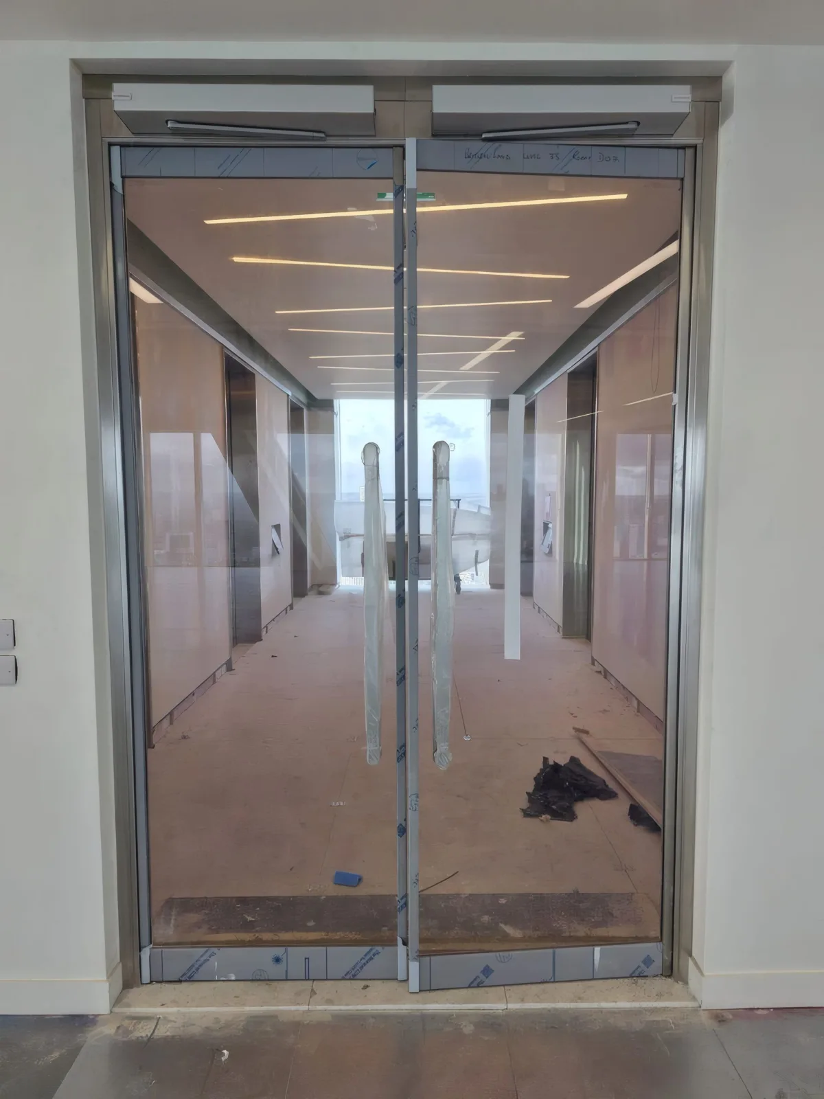 Completed fire-rated glazed double doors opening onto an internal corridor.