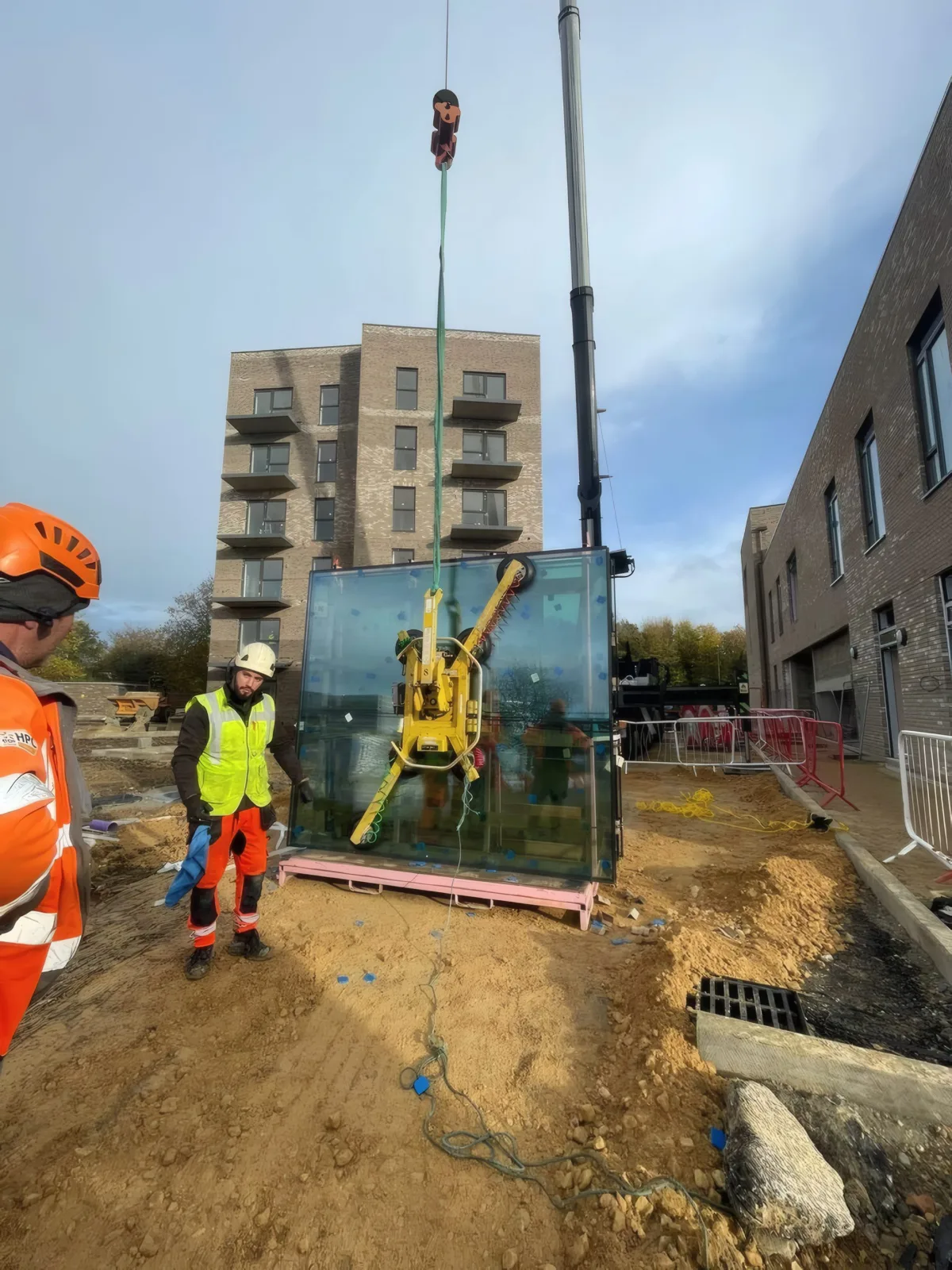 The OMFC International team positioning a glazing unit at ground level before it is craned into place.