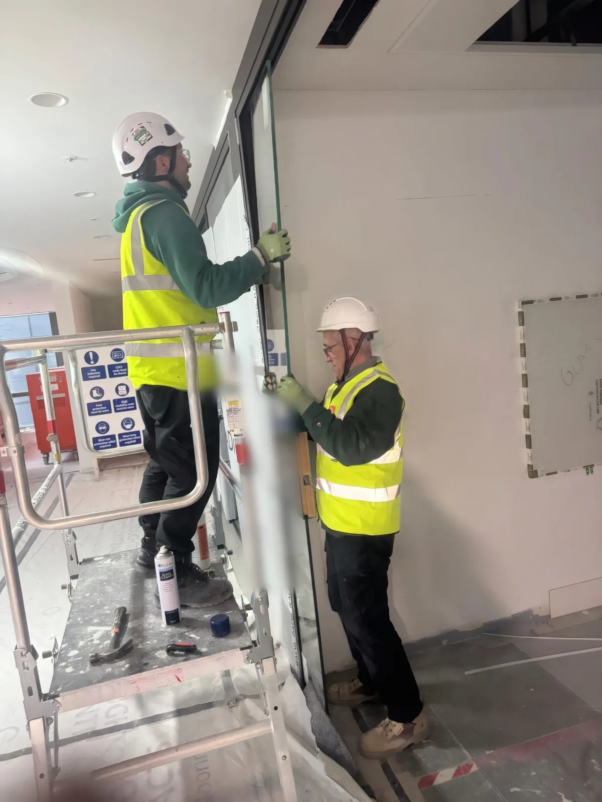 OMFC International installers fitting a glazed partition panel into position.