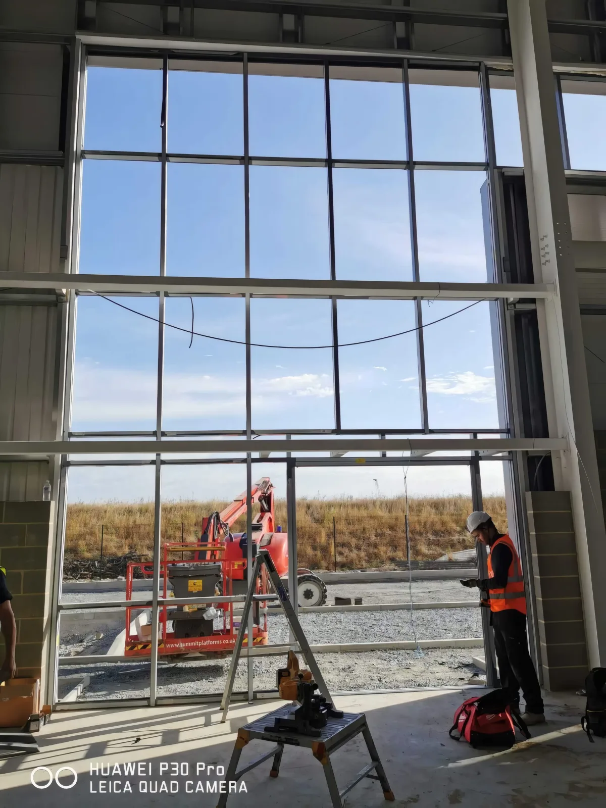 Inside a full-height glazed screen, with an installer at work.