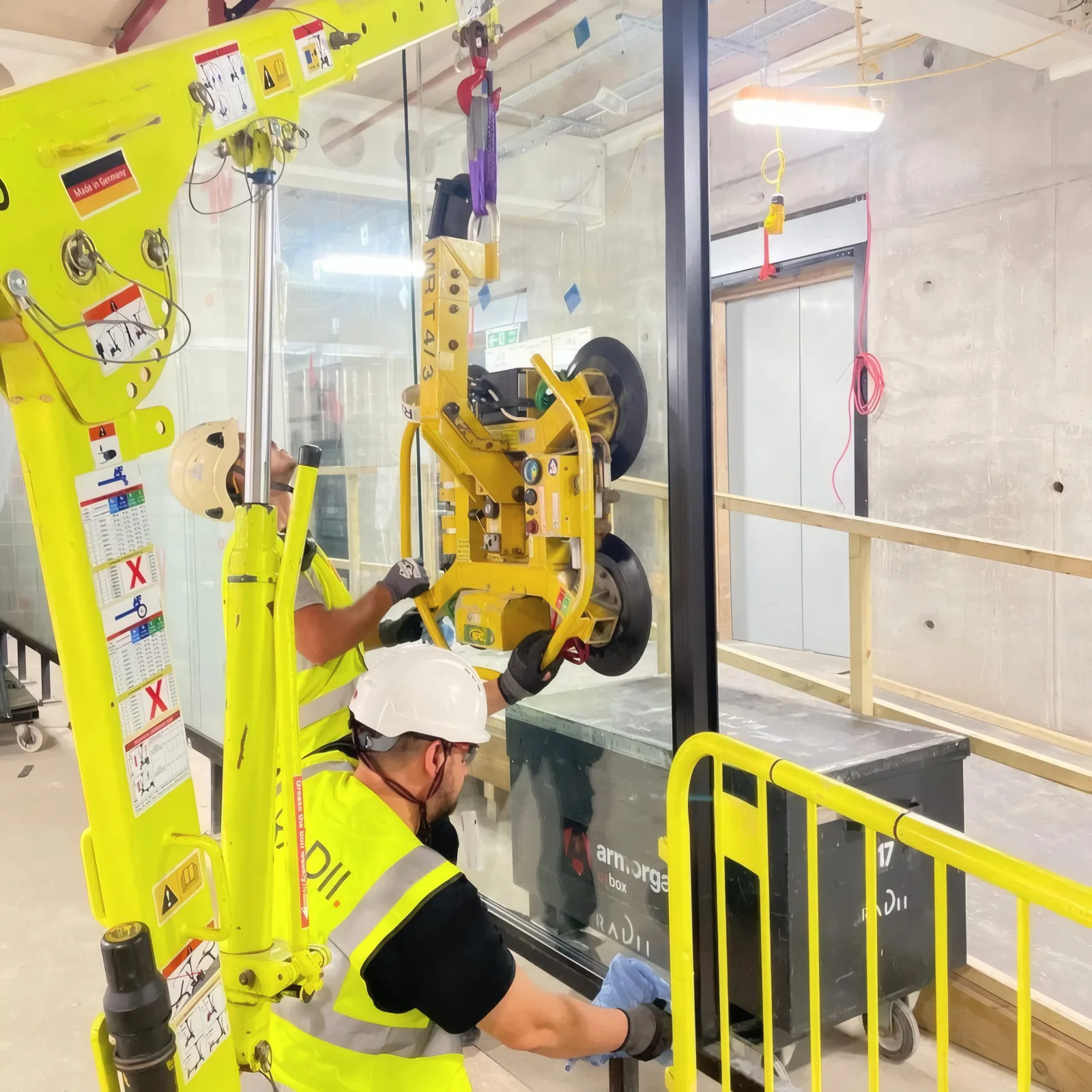 Close-up of the vacuum lifting equipment positioning a glazing unit during installation.