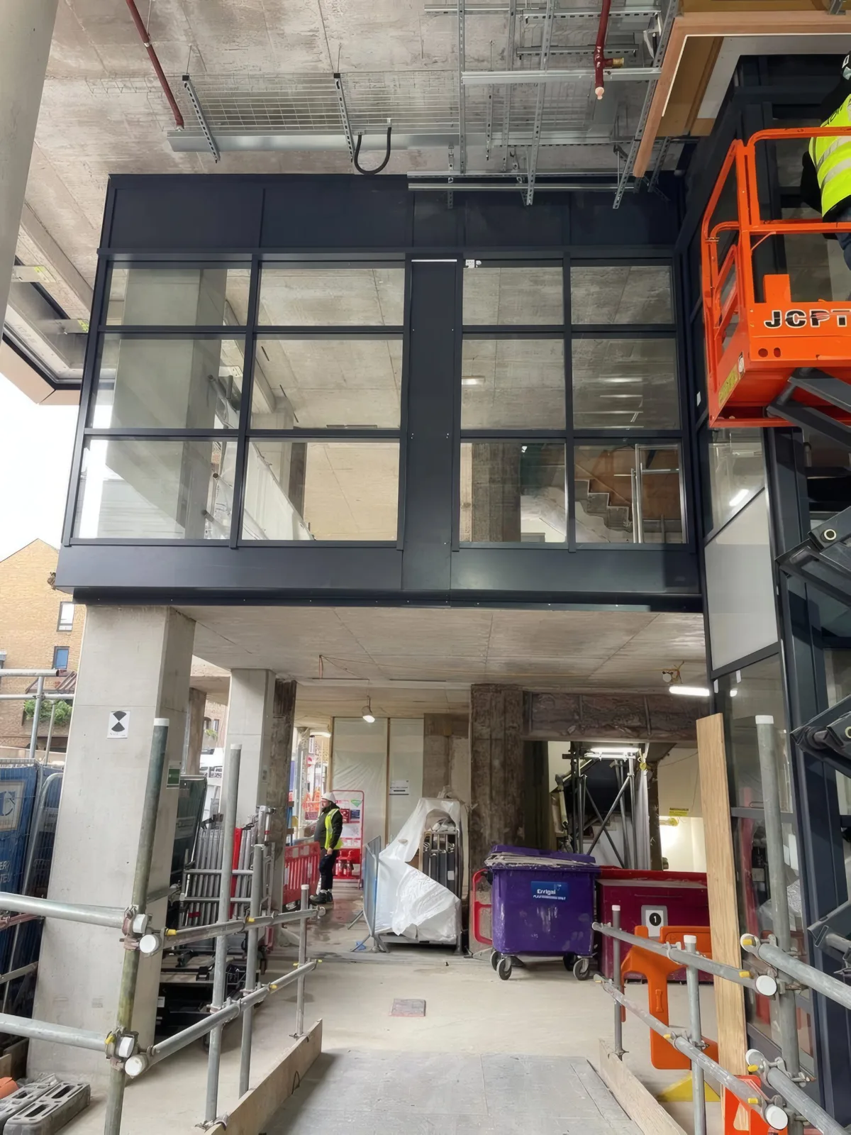 A black-framed glazed box at first-floor level, with a MEWP alongside.