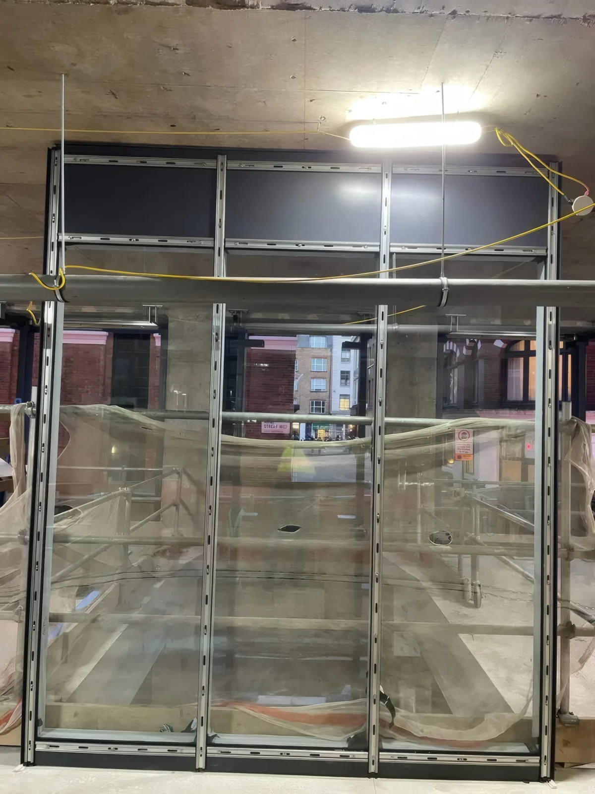 A glazed screen near completion, with the street visible through the new glazing.