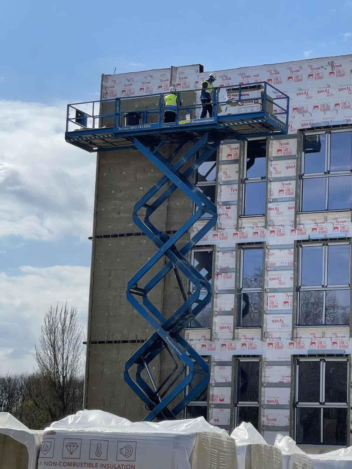 Operatives on a scissor lift fitting insulation and membrane to the upper floors.