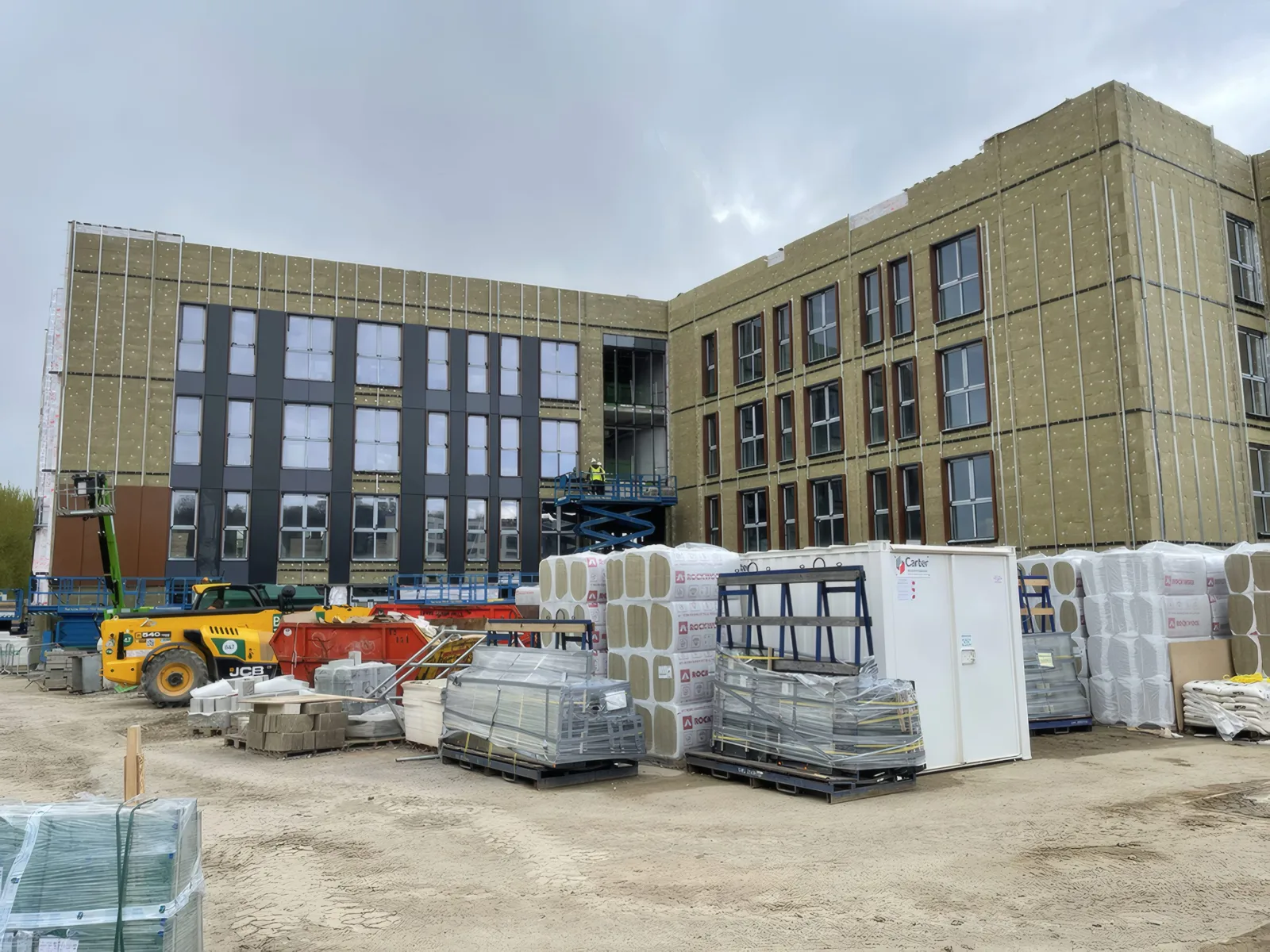 Insulated elevations awaiting cladding, with materials stored in the yard.