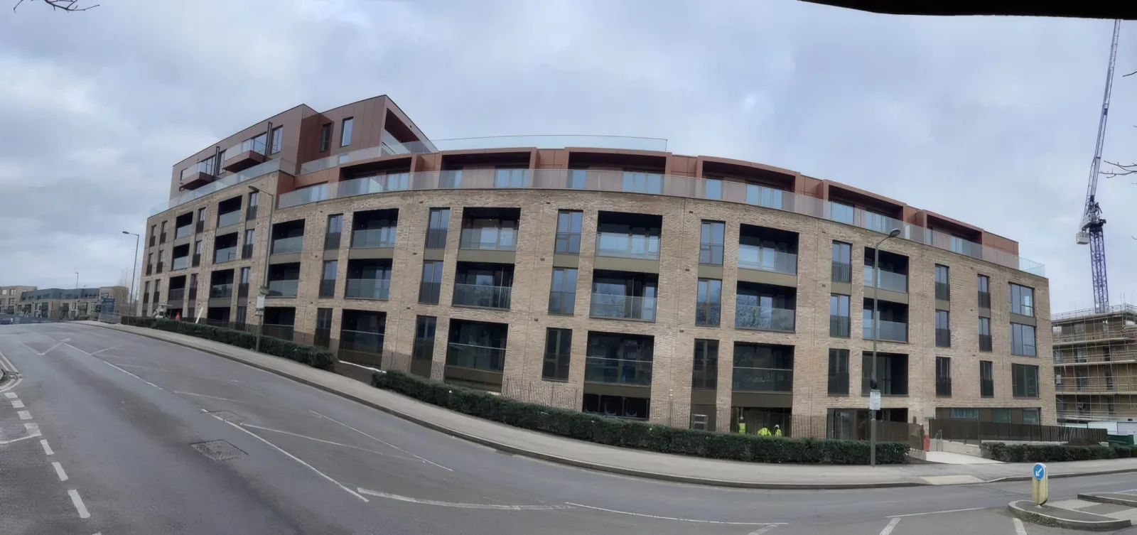 The completed residential development, showing the full curved brick facade with feature terracotta-finish cladding to the upper floors.