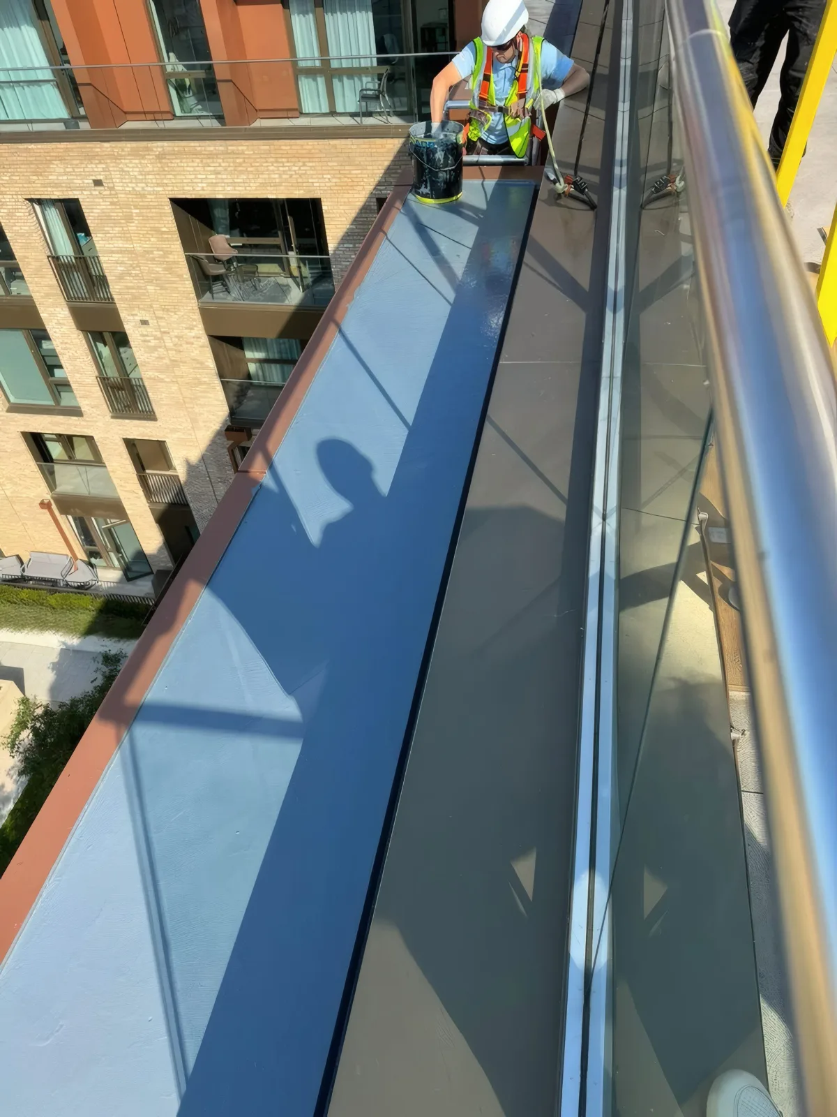 Applying waterproof membrane coating to a balcony parapet ahead of cladding installation.