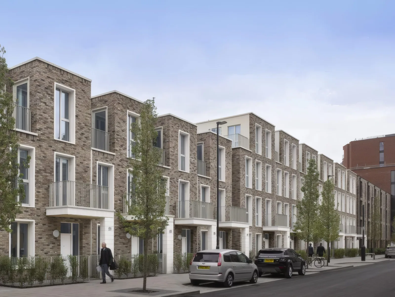A street of brick townhouses with planted front gardens.